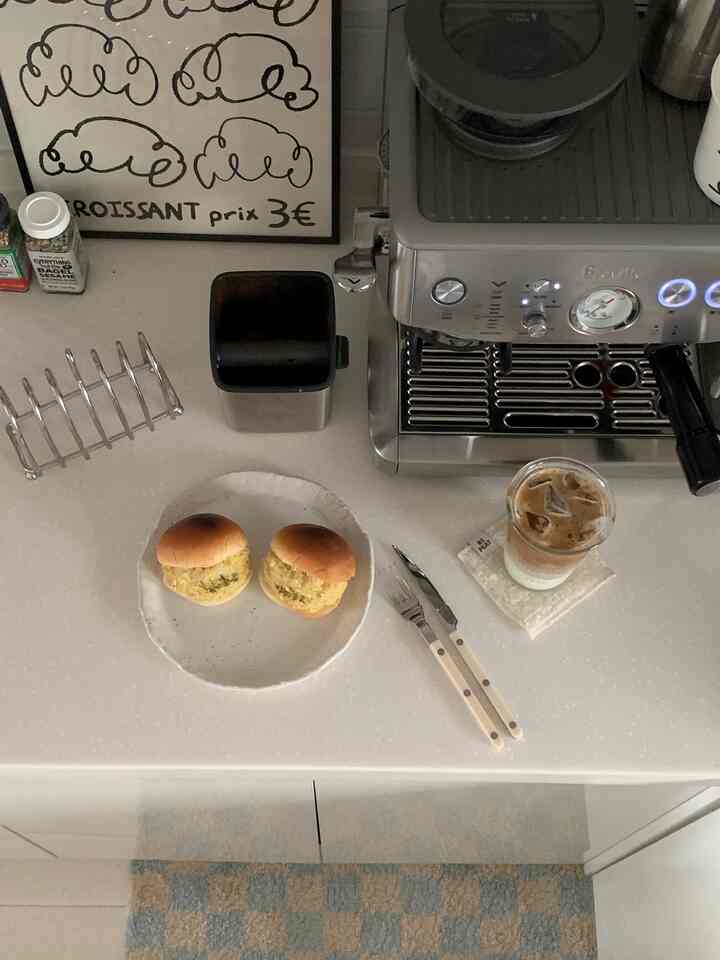 White and silver toned kitchen counter featuring an espresso machine, brunch plate, and iced coffee creating a tidy home cafe vibe