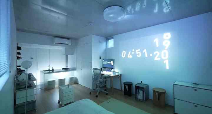 白と木目調の1Kスタジオ寝室、在宅勤務に適したシンプルでミニマルなホームオフィスが配置された空間