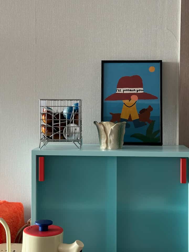 A minimal and cozy kitchen featuring a blue and red toned storage cabinet with decorative objects
