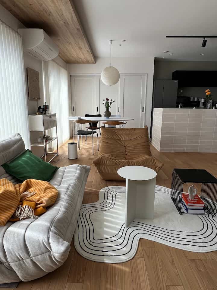 ナチュラルな色調のリビング、ベージュのソファとブラウンのチェアが配置された温かみのある印象的な空間