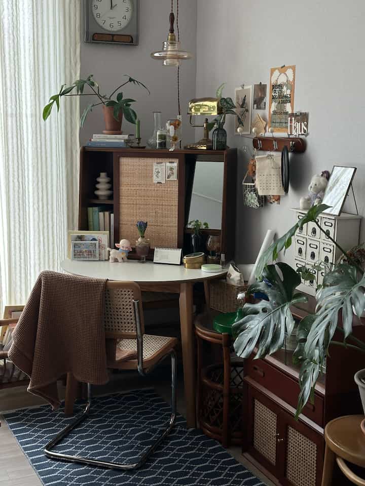 ナチュラルな木製家具とラタンがアクセントのリビング空間、中央に白い楕円形のデスクが配置された雰囲気あるインテリア