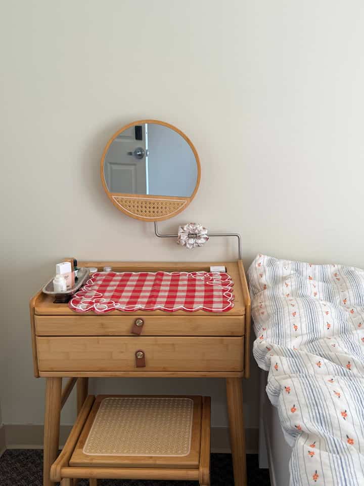 Beige-tone wall and natural wood vanity with stool arranged in a cozy bedroom space