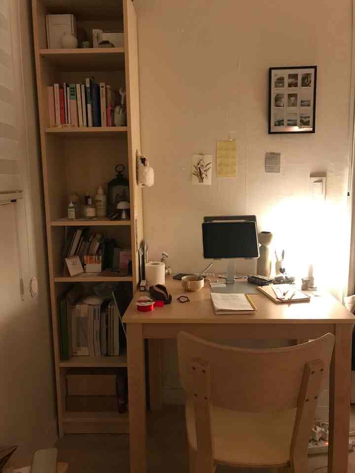 暖かい木目調の狭い部屋のワークスペース、木製デスクと椅子、本棚が配置された雰囲気のあるインテリア