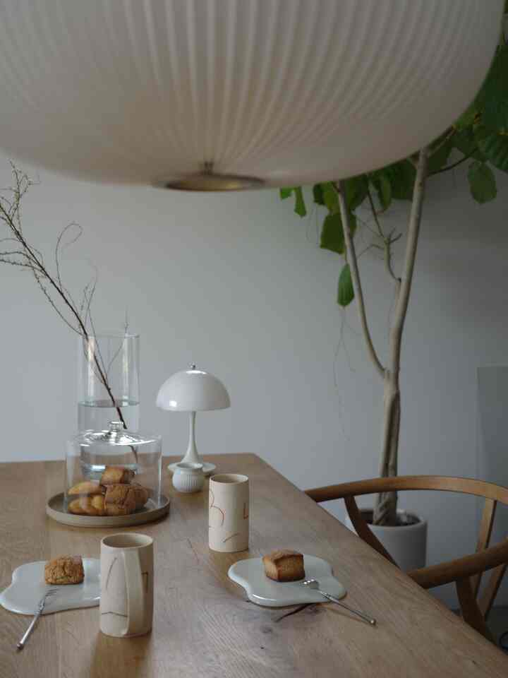 木目調のダイニングテーブルと白い照明があるモダンなダイニングルーム、シンプルで自然な雰囲気のインテリア