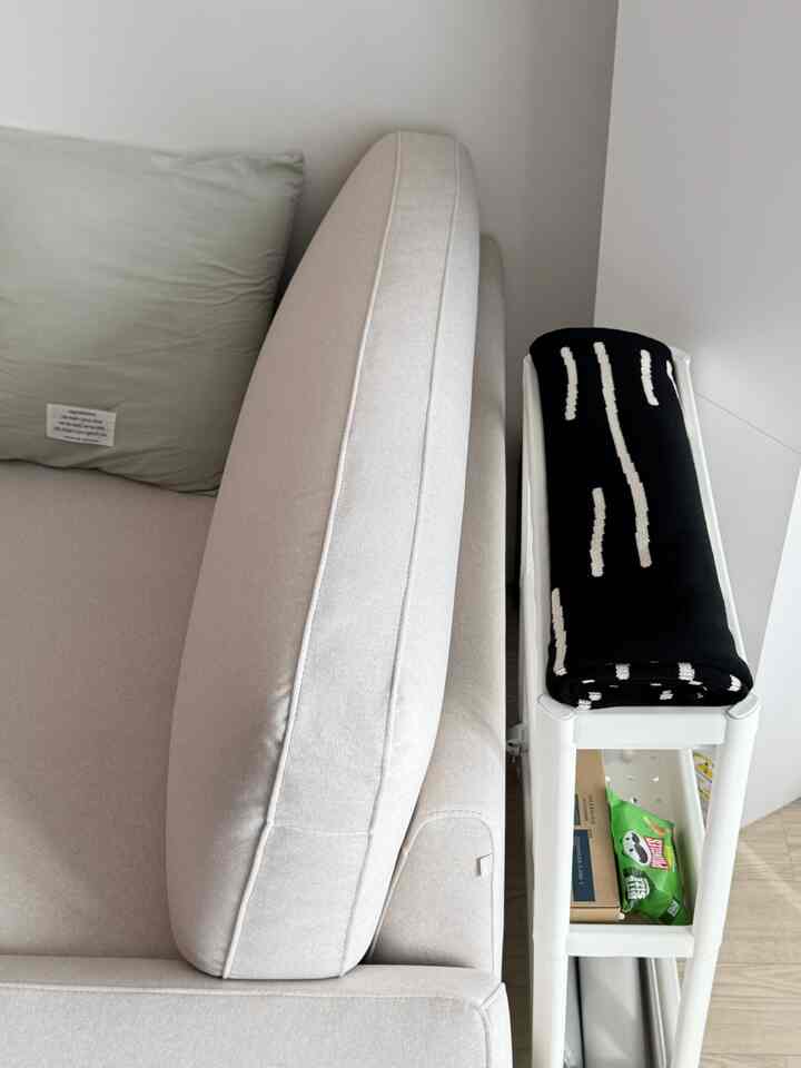 ホワイトとベージュのトーンで統一された隙間収納とソファが配置された清潔感ある空間