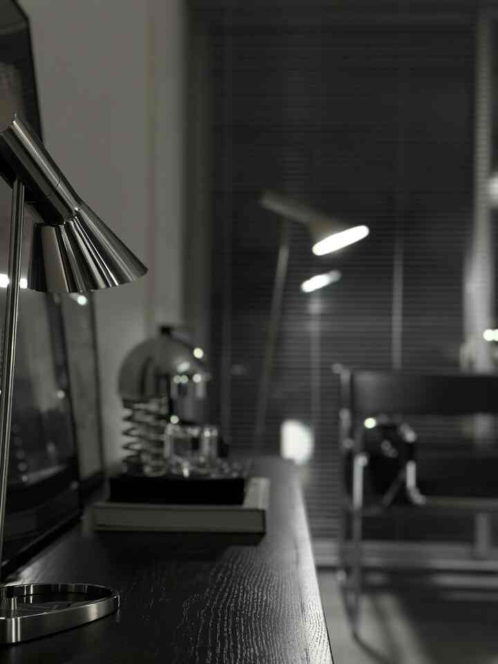 黒とシルバーのトーンのモダンなホームオフィス、金属製のテーブルランプとフロアランプが配置された洗練された空間