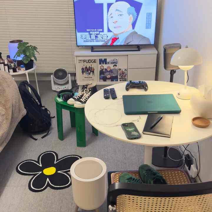 白を基調とした小さなリビング、丸テーブルとテレビ台、ミニマルな家具配置とゲーム用小物のある雰囲気のあるインテリア