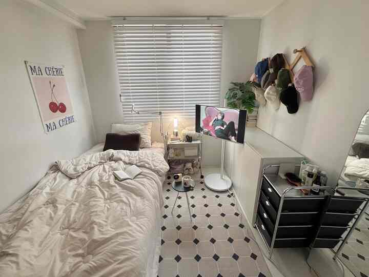 ホワイトトーンのワンルーム寝室、一人用ベッド、ブラインド、トロリー引き出し、キャビネットが配置された雰囲気ある空間