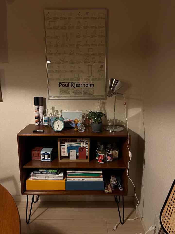 Warm wood tone living room featuring a poster, lamp, and plant arranged in a cozy setup