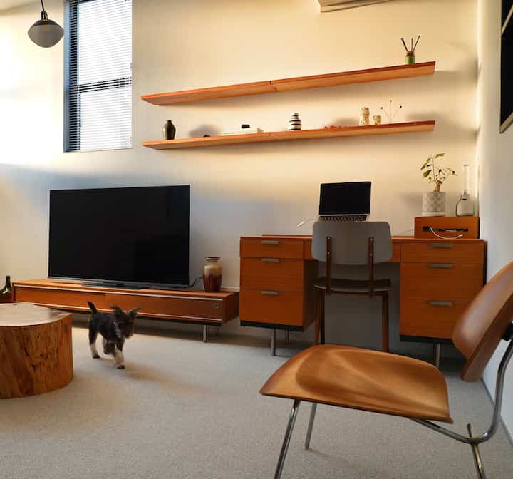 Warm wood tones and beige carpet harmonize in a living room featuring a desk with a laptop suitable for home office