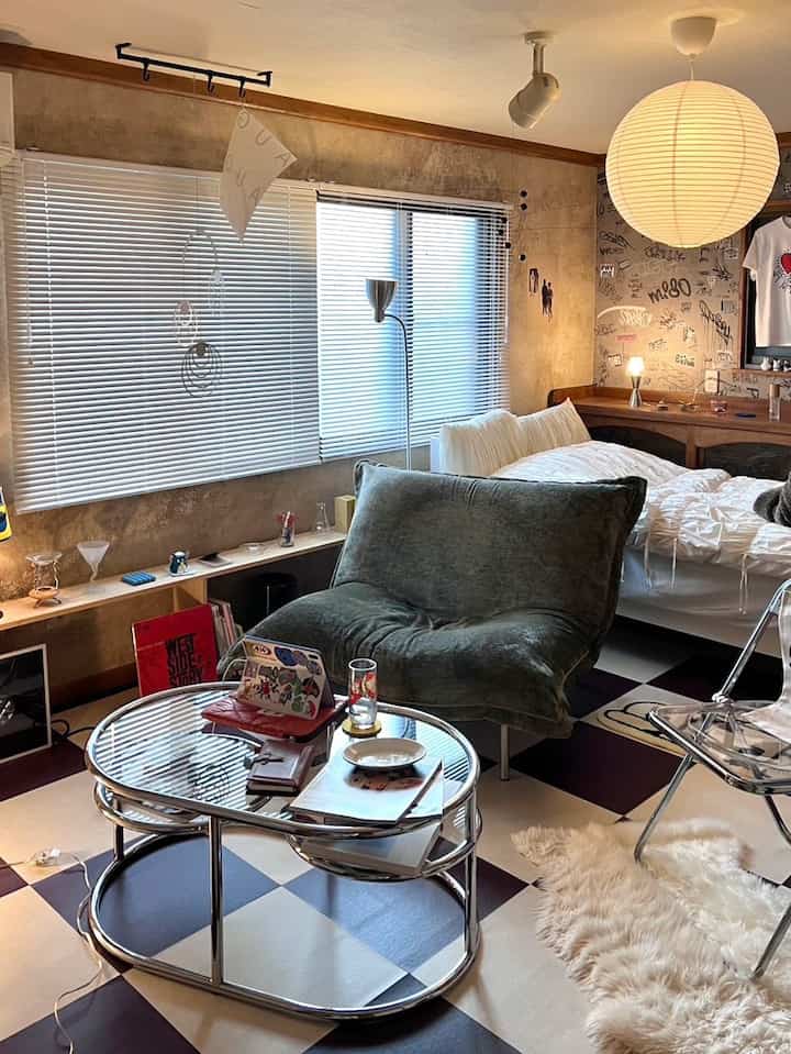 White and brown toned studio apartment living-bedroom space featuring mid-century modern sofa and coffee table with cozy atmosphere