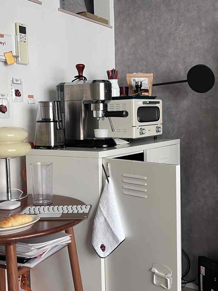 ホワイトとブラウン調のコンパクトなキッチン空間、モダンなコーヒー器具とタオルが配置された一人暮らし向けのインテリア