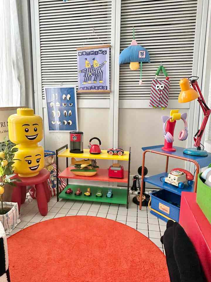 Bright yellow and red-accented veranda space featuring Lego head storage, various toys, and posters in a charming interior accessories setup