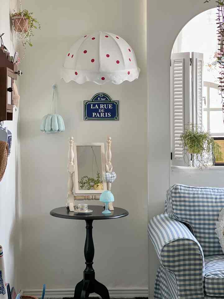 白と青の色調のリビング、チェック柄ソファと黒の丸いサイドテーブル、フレンチカントリースタイルのかわいらしいインテリア