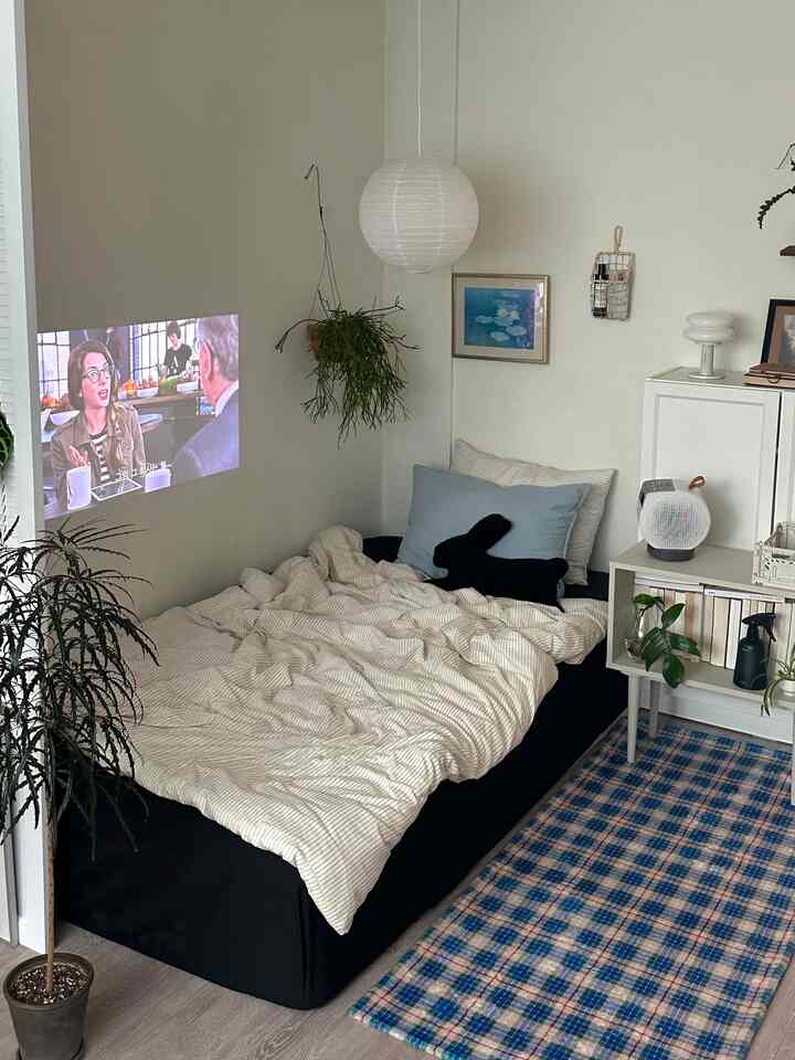 Beige-toned bedroom with a black mattress cover and blue cushions in a cozy studio apartment space