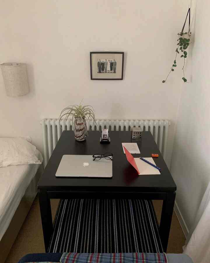 黒と白のトーンの寝室とデスク、机の上にノートパソコンとメガネ、植物が配置されたモダンな空間