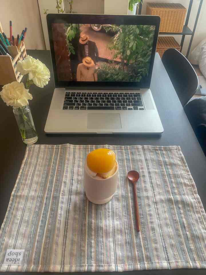 ナチュラルな雰囲気の黒いデスクにヴィンテージ風のストライプのテーブルランナーとデザートが置かれたおうちカフェの空間