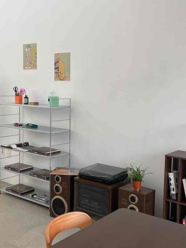ウッドトーンと金属製の棚があるシンプルなリビング、オーディオ機器と本棚が配置された雰囲気のある空間