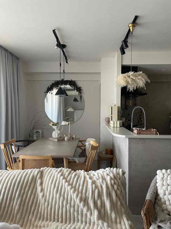 Beige and natural tone dining room featuring large round mirror and wooden dining chairs with cozy atmosphere