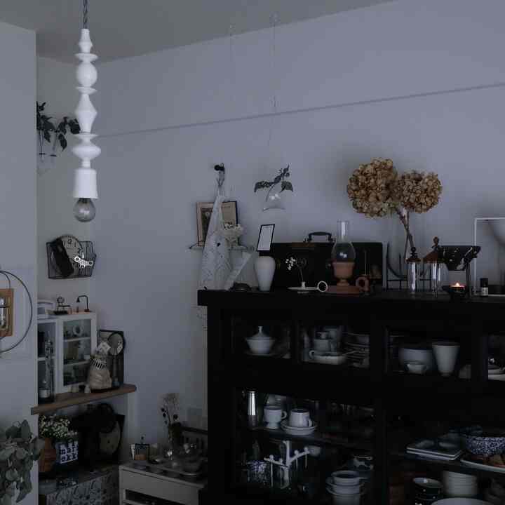 白い壁と黒いキャビネットのあるリビング、アロマディフューザーとアンティーク装飾が配置されたモノトーンの雰囲気あるインテリア