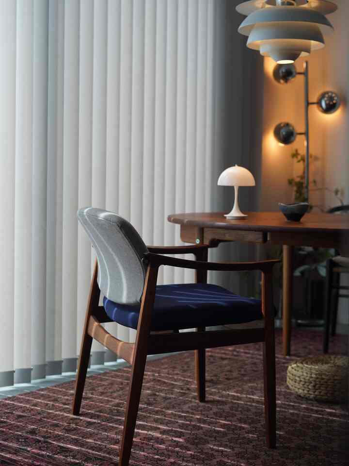 Wood tone Nordic dining room featuring a wooden dining table with blue cushioned armchair, pendant lighting, and a warm cozy atmosphere