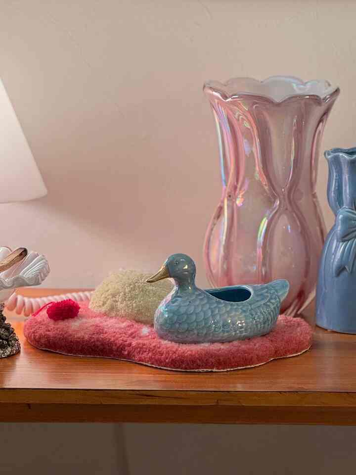 木目調の棚にパステルブルーのフレンチヴィンテージ風のアヒルの陶器と花瓶が配置されたナチュラルカラーの印象的なインテリア