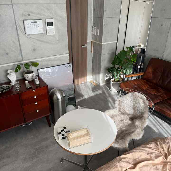 Mid-Century Modern living room with gray concrete walls and floor, brown leather sofa, and white round table