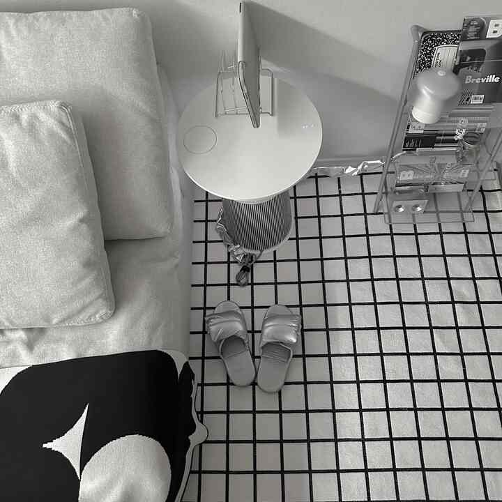 Modern living room in white and silver tones featuring a sofa, checkered rug, and side table creating a clean atmosphere