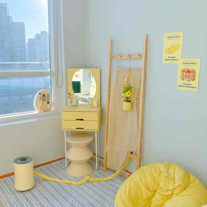 柔らかな黄色のトーンと木製ラダーがある明るい窓辺の居心地の良いミニマルなリビングルーム