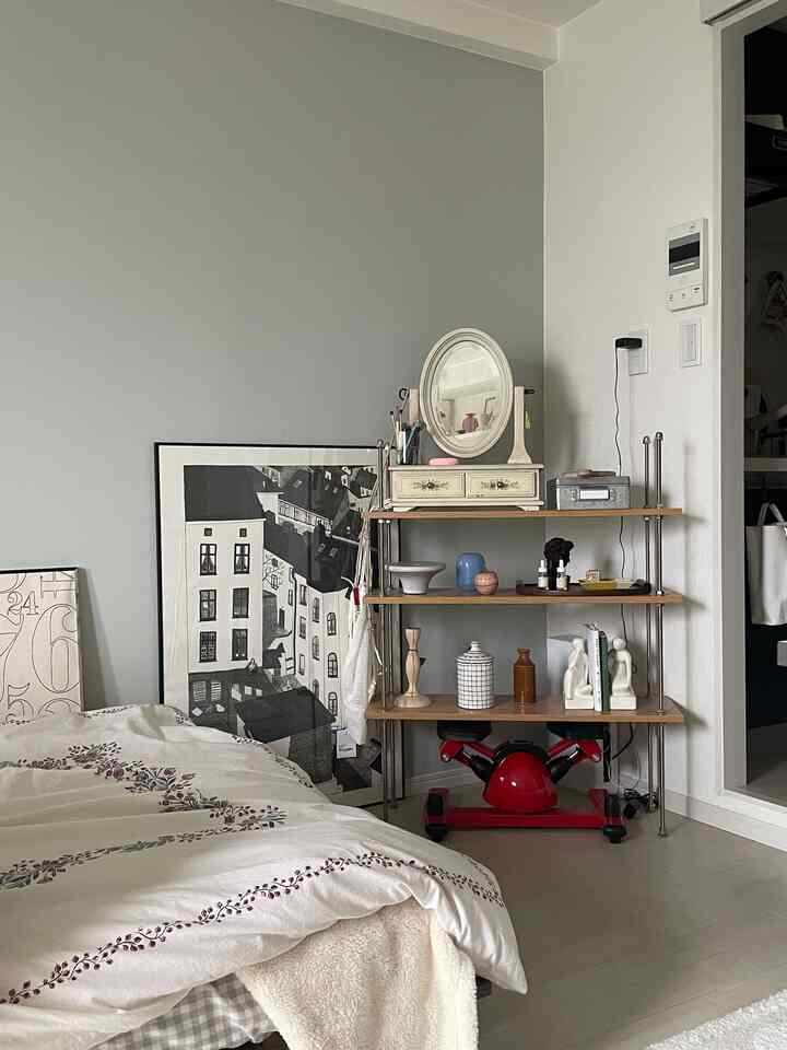 White and gray toned single household 1K living room featuring vintage style poster and shelf with cozy atmosphere