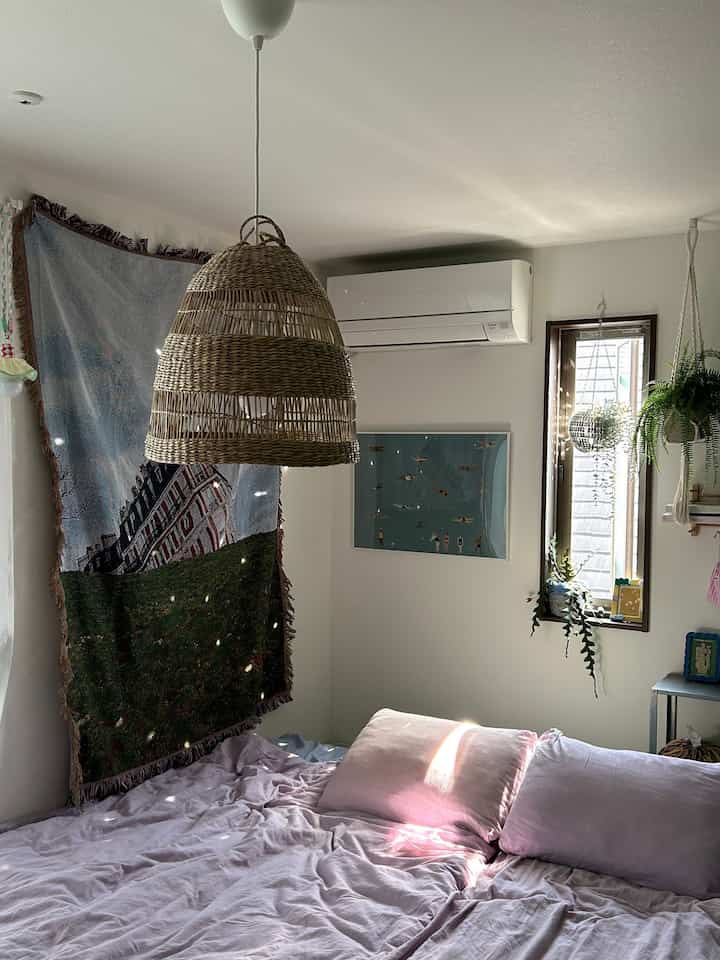 White-walled bedroom featuring natural wood-tone pendant light and soft pink bedding for a cozy atmosphere