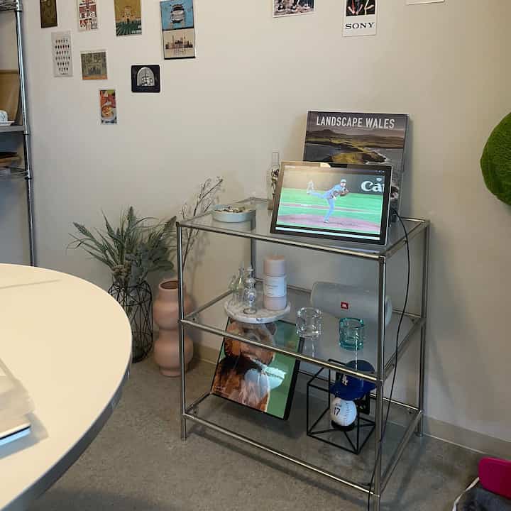 Transparent glass shelf with metal frame mid-century modern living room featuring a white round table and decorative vases in a tidy space