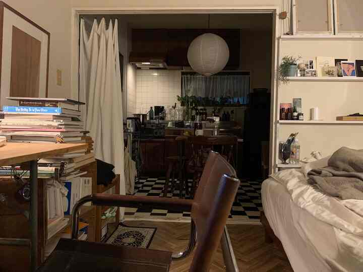 Small apartment bedroom and kitchen space featuring warm brown and clean white tones with natural wood elements