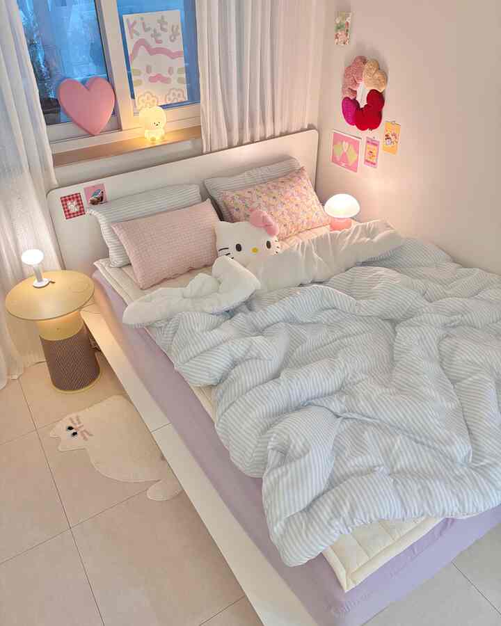 White and pink-toned bedroom featuring cat-themed posters and cushions, creating a cozy and bright atmosphere