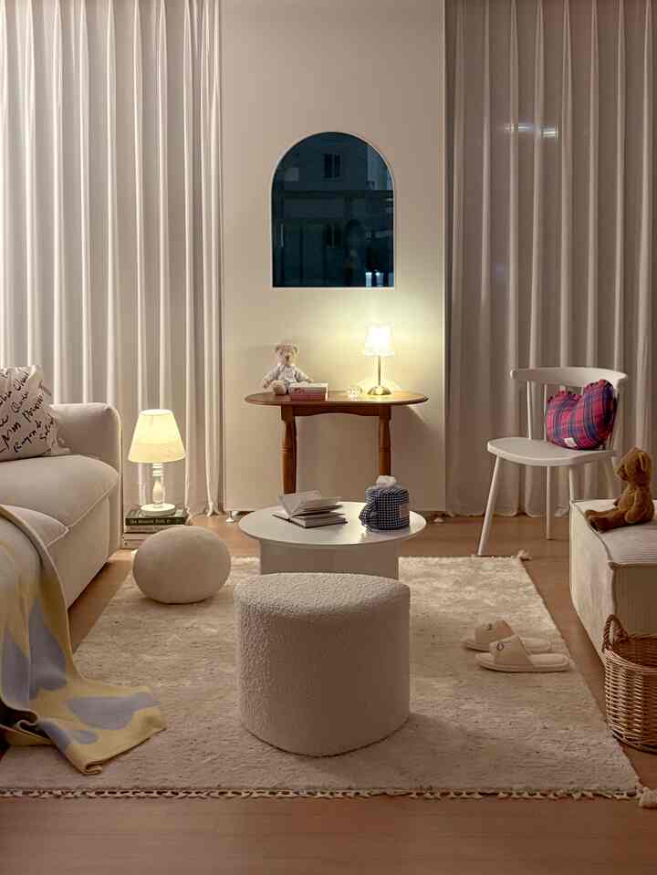 Beige and white toned living room featuring a wooden side table, round coffee table, and plush rug creating a cozy atmosphere