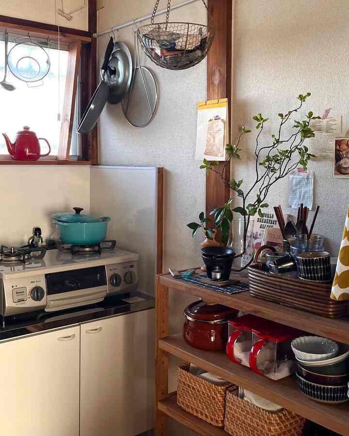 ベージュと木目調のコンパクトなキッチン、ガスコンロと棚に整ったキッチン用品が配置された雰囲気のある空間