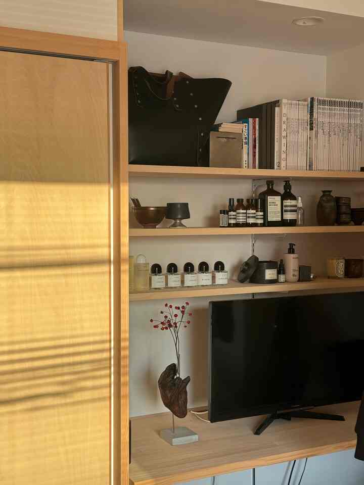 ナチュラルな木目調の1LDKリビング、棚やキャンドル、テレビが配置され、落ち着いた雰囲気のあるインテリア