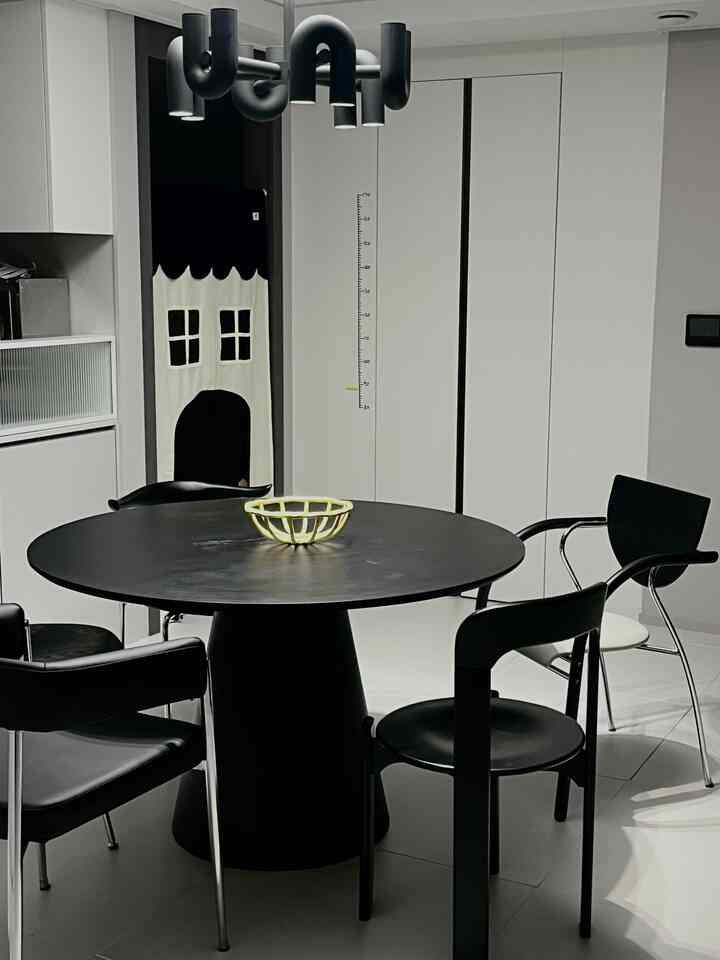 Modern white-toned living room featuring a black round dining table and black chairs