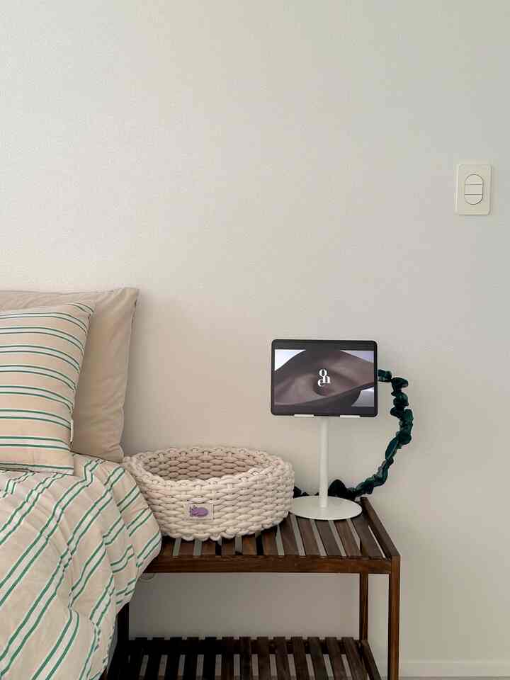 Natural style bedroom with white walls and brown wooden nightstand, featuring a knitted cat basket and pillows in a cozy setting
