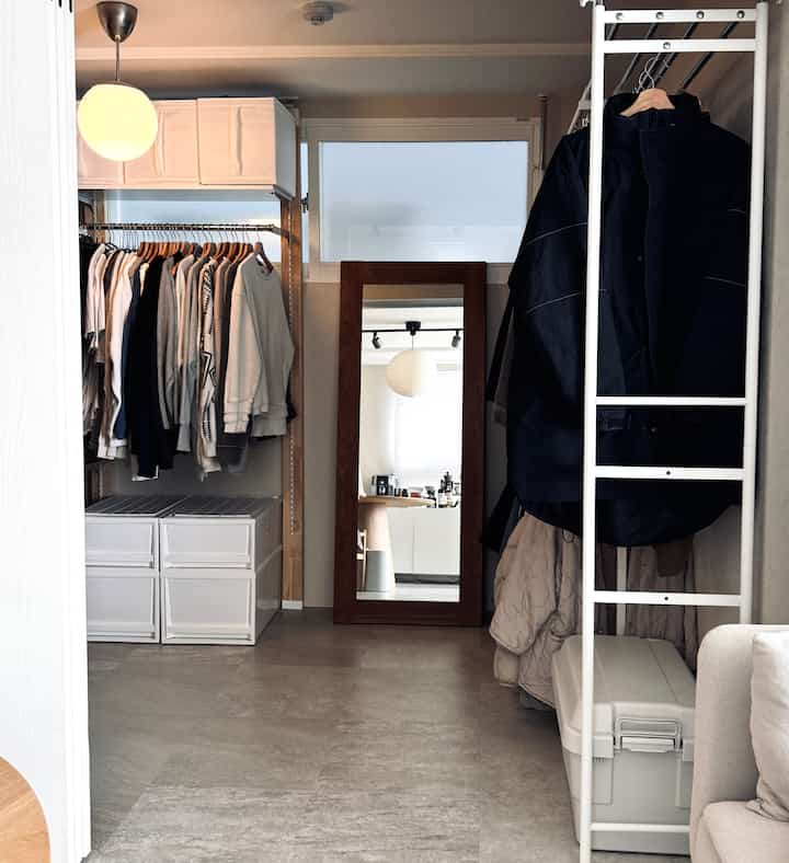 White and gray toned walk-in closet featuring metal frame wardrobes and storage boxes in a clean organized space