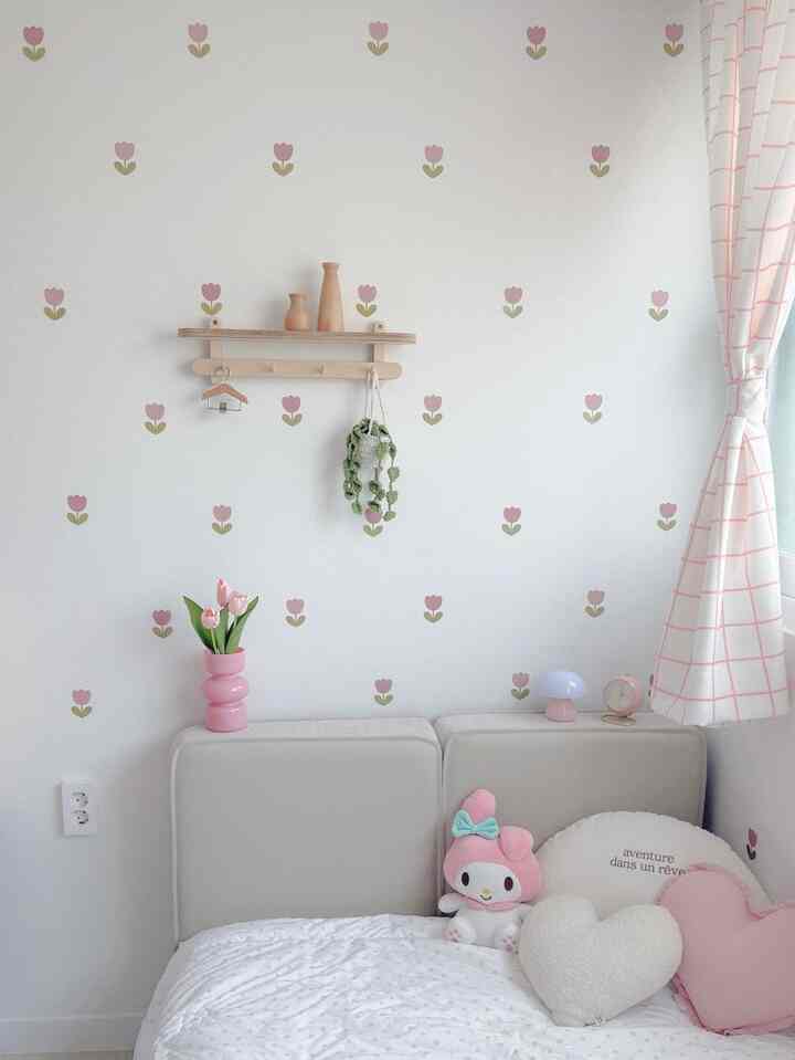 Pink and beige toned kids' room featuring cute tulip wallpaper, cozy cushions, and patterned curtains creating a warm atmosphere