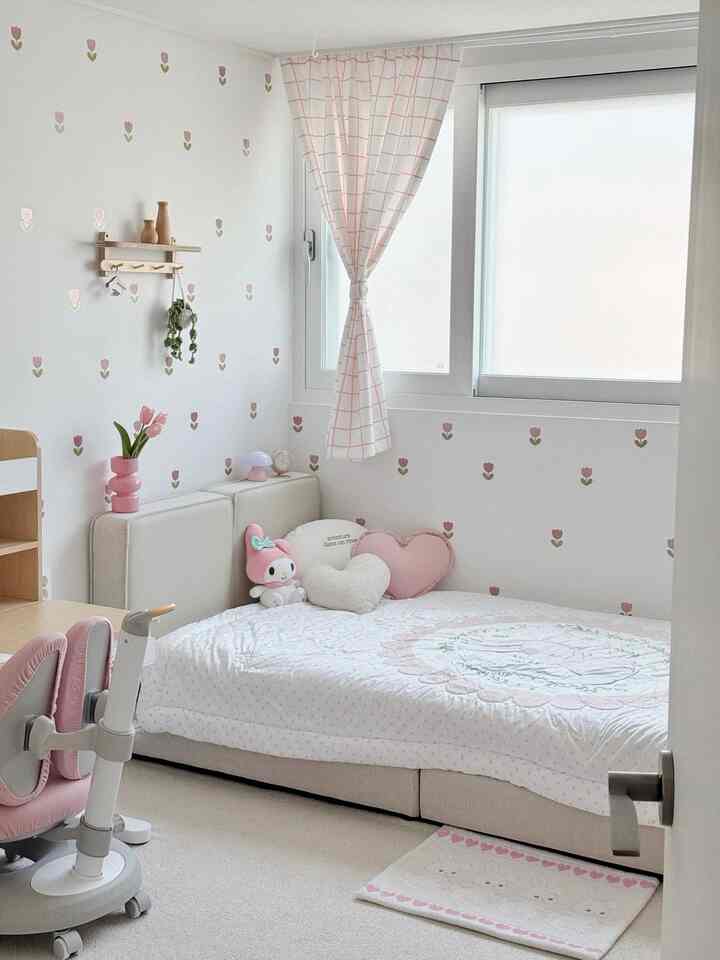 A pink-toned kids' room featuring tulip wall stickers, a low bed, and a desk, creating a warm and charming atmosphere