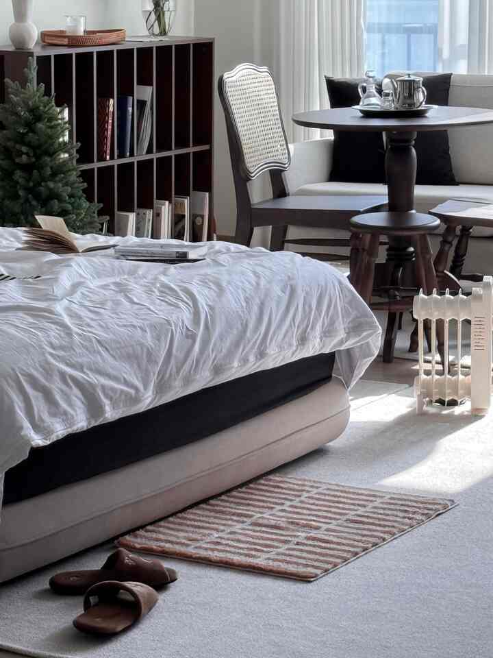 Natural and cozy bedroom with white and beige tones featuring bed, sofa and dining table