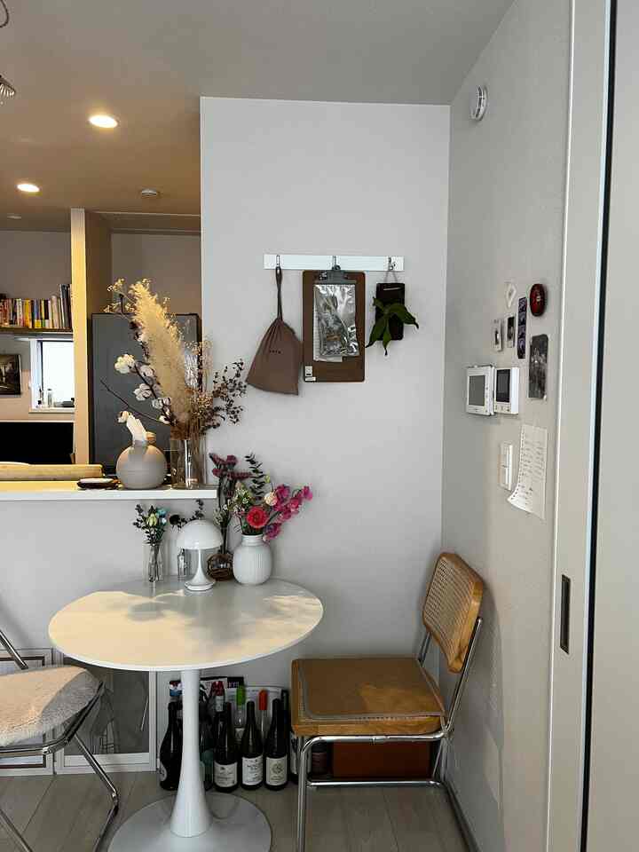 白と木目調の調和が感じられるコンパクトな一人暮らし用ダイニングスペース、花瓶や小物で自然な雰囲気を演出