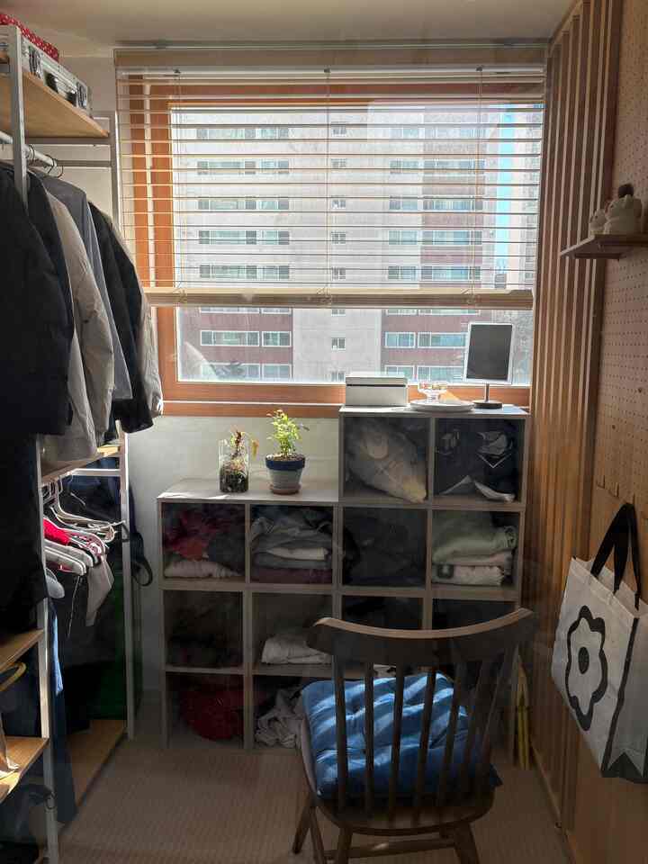 ウッドトーンとブラウンの色合いが調和したベランダ、パーティションで区切られた猫トイレとウォークインクローゼットのある居心地の良い狭い部屋