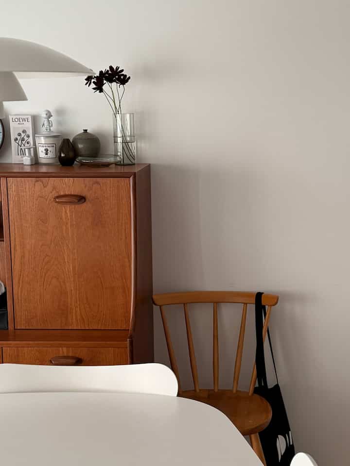 ナチュラルな木目調と白を基調としたダイニング、ヴィンテージキャビネットとアーコールチェアが調和するシンプルな空間