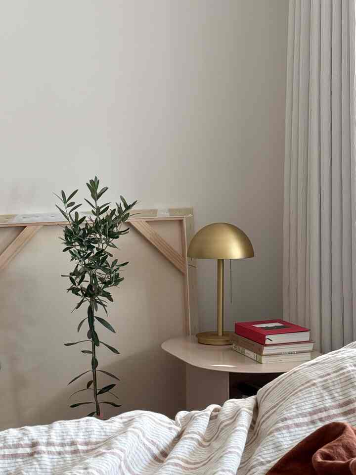 Beige toned bedroom featuring a gold lamp and a leafy plant creating a cozy atmosphere