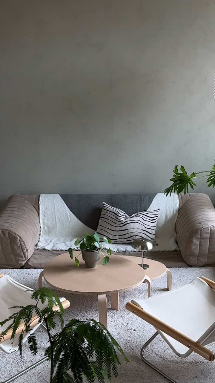 ナチュラルな色調のリビング、ローソファとローテーブル、観葉植物が配置されたシンプルな空間