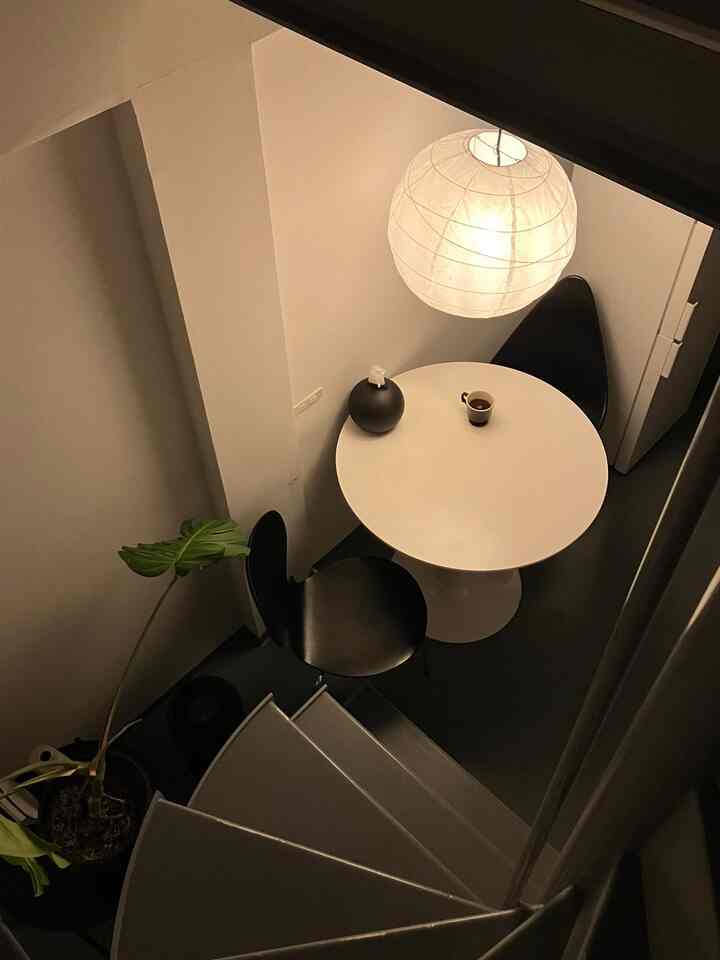 ナチュラルな色調の狭いダイニングスペース、白い丸テーブルと黒い椅子、イケアの和紙ペンダントライトが温かみのある雰囲気を演出