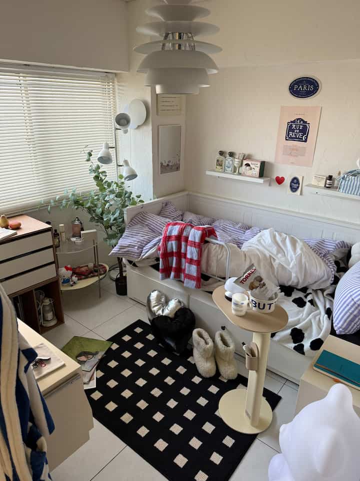 Natural and white toned small living room featuring a storage daybed, plants, and cozy decor items